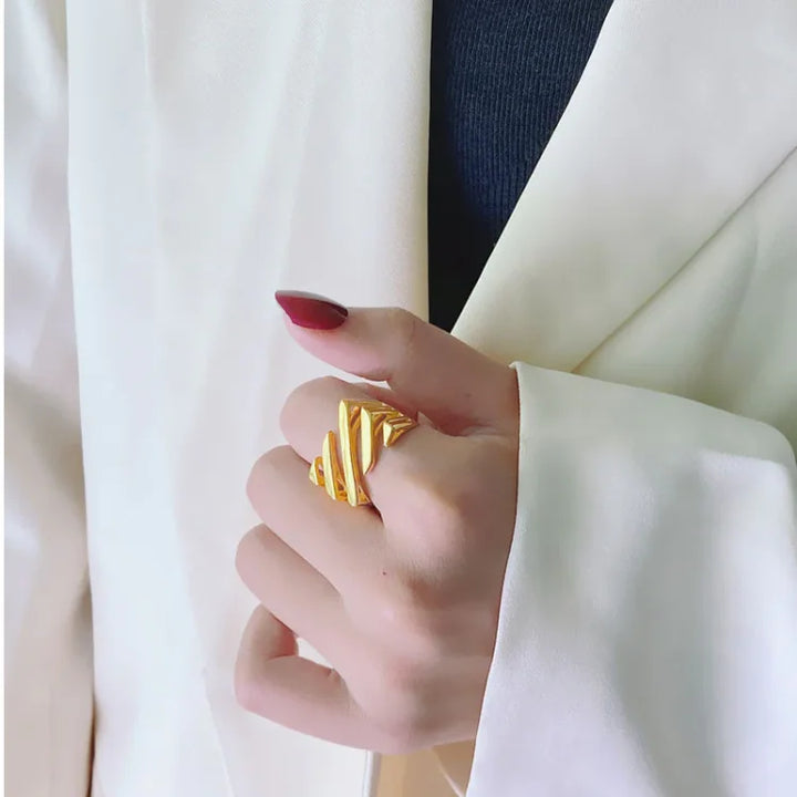 Goldener Ring, Damenmode, elegantes Design, Schmuck, Accessoire, stilvoll, Hand, weißer Blazer.