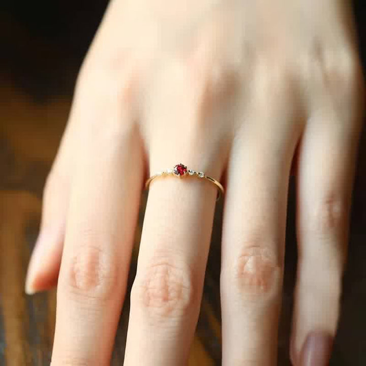 Goldener Ring mit rotem Edelstein auf Hand, eleganter Schmuck, Damenring, feine Details.