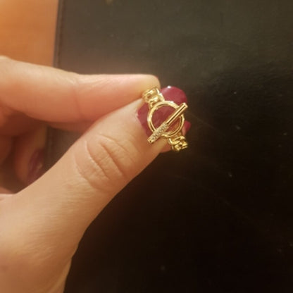 Hand hält goldenen Ring mit rotem Herzstein, elegantes Schmuckdesign, Damenmode Accessoire.