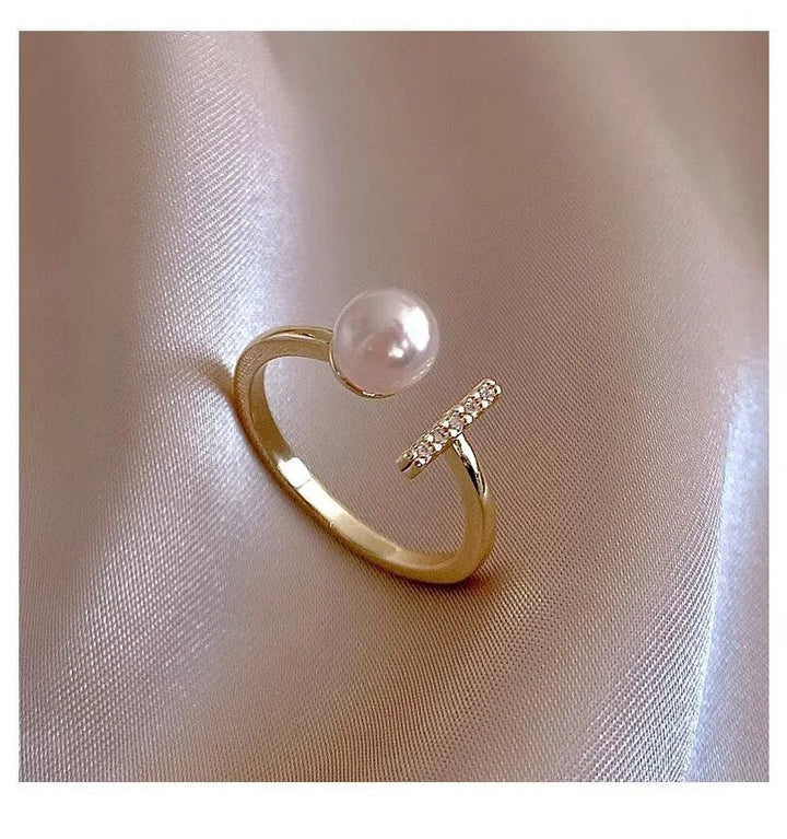 Goldener Ring mit Perle und Diamanten auf Seide, eleganter Schmuck, luxuriöses Design.