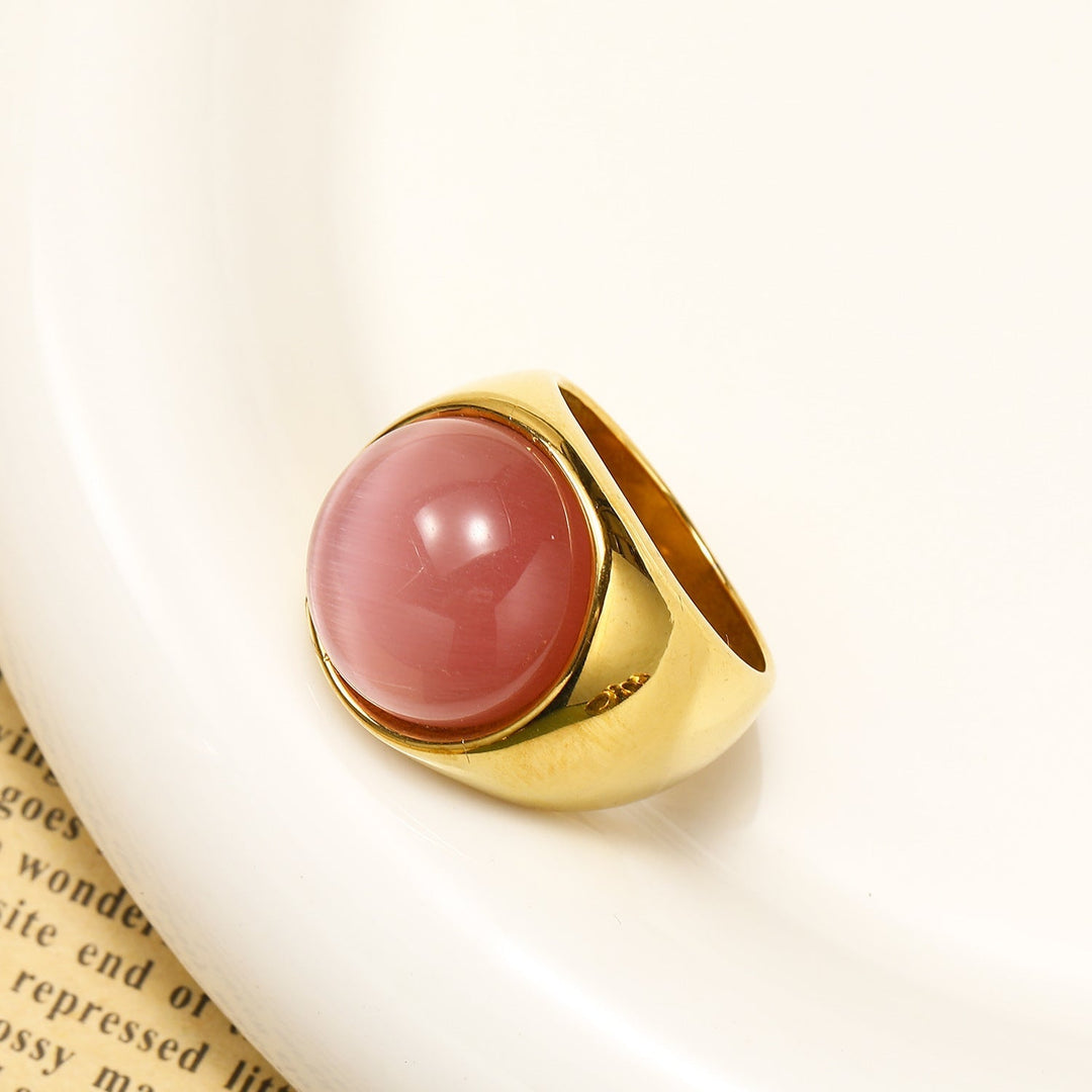 Goldener Ring mit rundem rosa Stein, elegantes Schmuckdesign, luxuriöses Accessoire.
