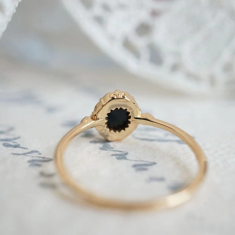 Goldener Ring mit schwarzem Edelstein, filigranes Design, eleganter Schmuck für Damen.