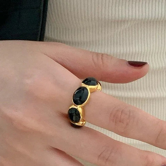 Goldener Ring mit schwarzen Steinen, elegantes Schmuckdesign, Damenmode Accessoire.