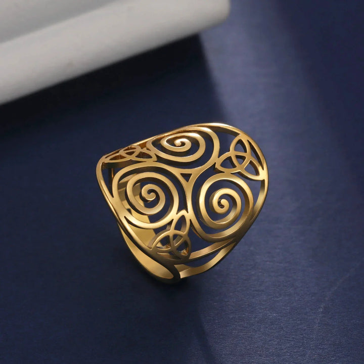 Goldener, filigraner Ring mit Spiralmuster auf blauem Hintergrund, eleganter Schmuck.