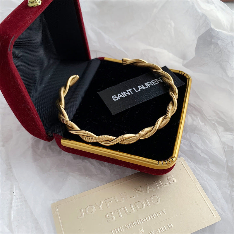 Goldener Edelstahl-Twist-Armreif in roter Schmuckschatulle, elegantes Damen-Accessoire.