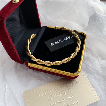 Goldener Edelstahl-Twist-Armreif in roter Schmuckschatulle, elegantes Damen-Accessoire.