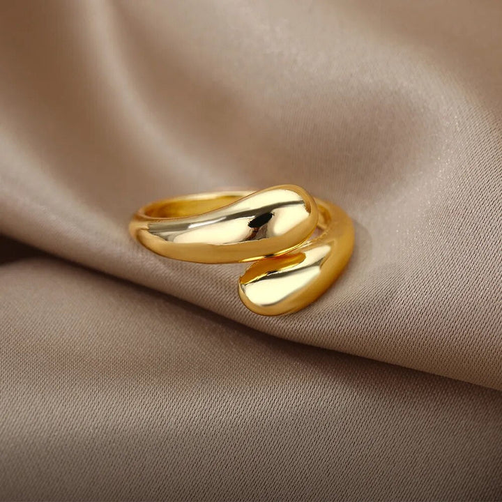 Goldener, geschwungener Ring auf beigem Stoff, elegantes Schmuckdesign, glänzend, modisch.