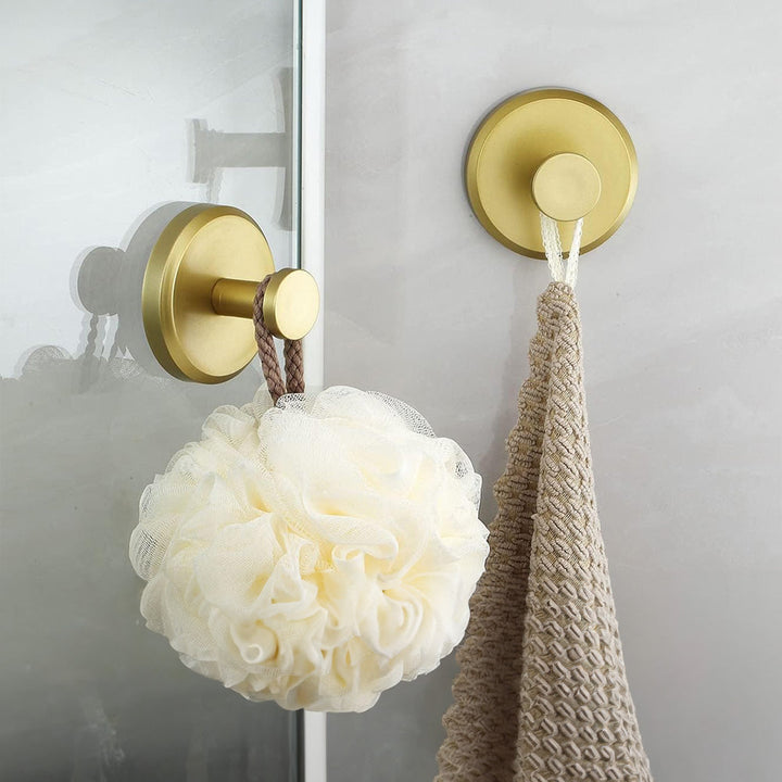 Goldener Wandhaken im Badezimmer mit Duschschwamm und Handtuch, modern, stilvoll, platzsparend.