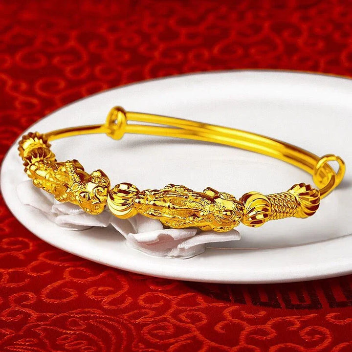 Goldenes Armband mit Drachenmotiv, verstellbar, auf rotem Hintergrund, Schmuckdesign.