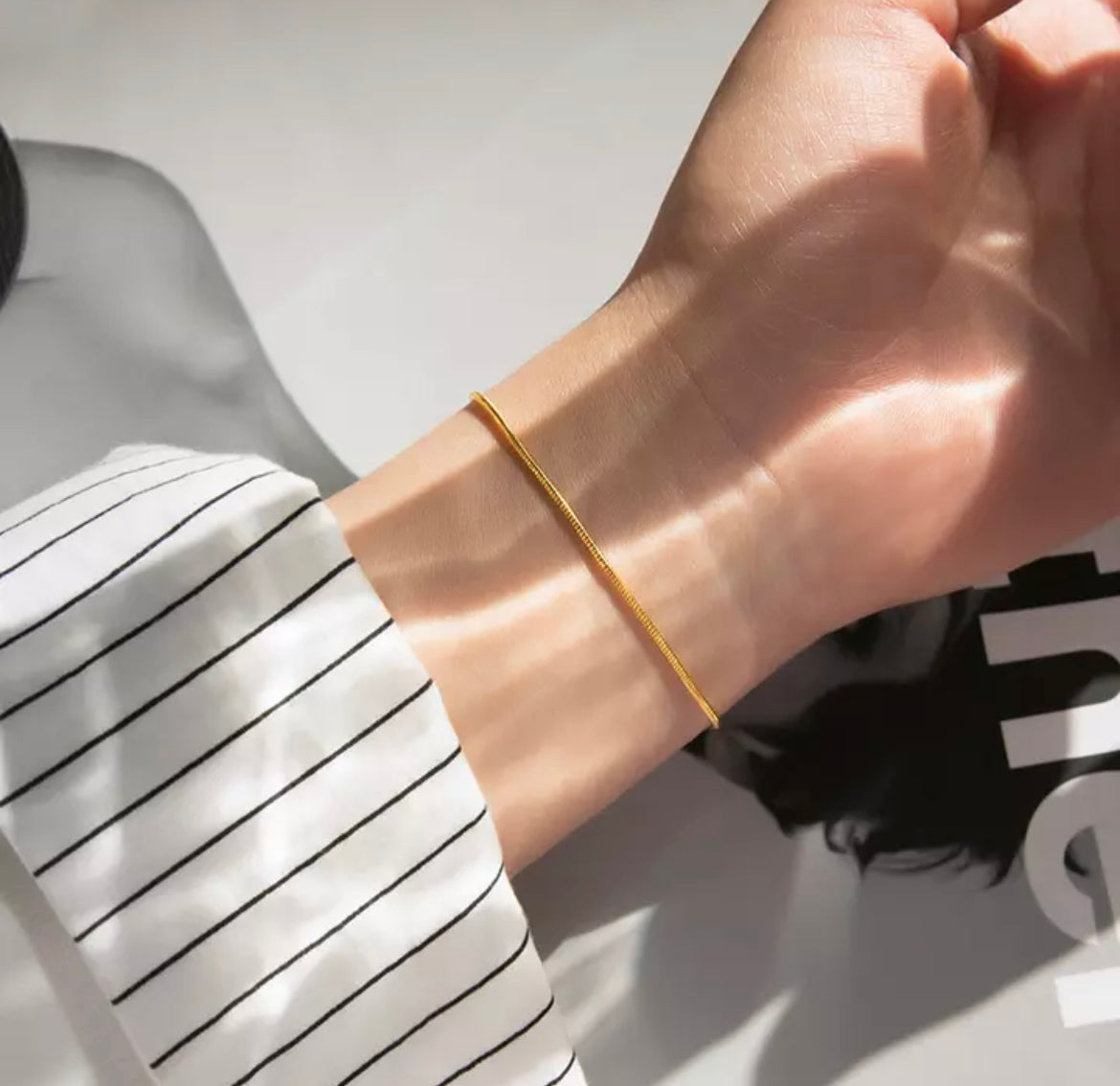 Goldenes Armband am Handgelenk, minimalistisches Design, eleganter Schmuck für Damen.