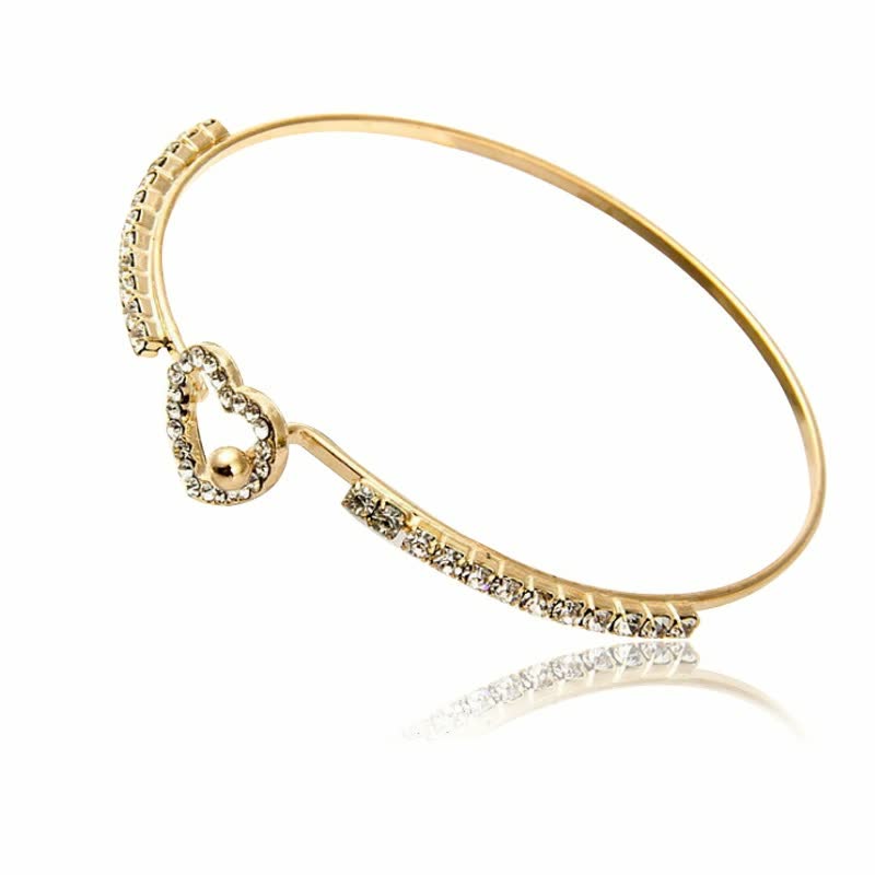 Goldenes Armreif mit Herzanhänger und Kristallen, eleganter Schmuck für Damen.