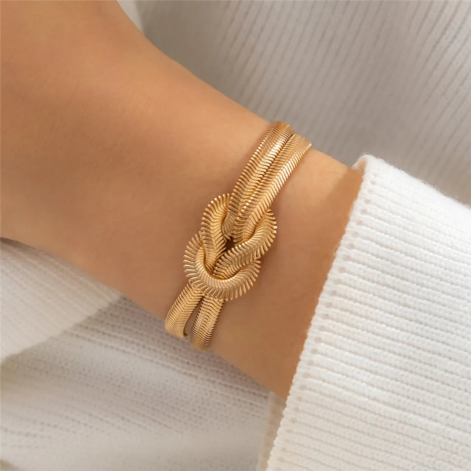Goldenes Armband mit Knoten-Design auf Handgelenk, eleganter Schmuck, Damenmode.