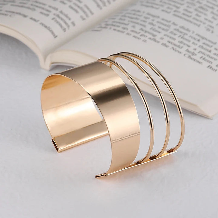 Goldenes Armreif-Set aus Metall, modernes Design, offen, vor aufgeschlagenem Buch.