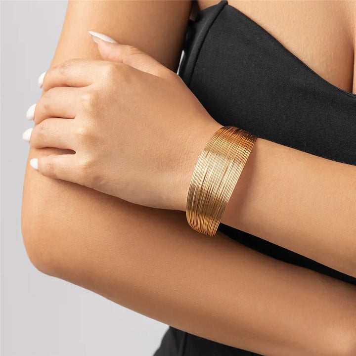 Frau trägt elegantes, goldenes Armband aus Metall, modisches Accessoire, Nahaufnahme.