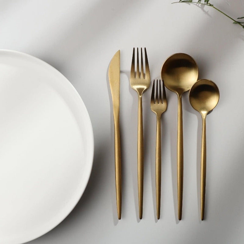 Goldenes minimalistisches Besteck-Set auf weißem Hintergrund, bestehend aus Messer, Gabel, Löffel.