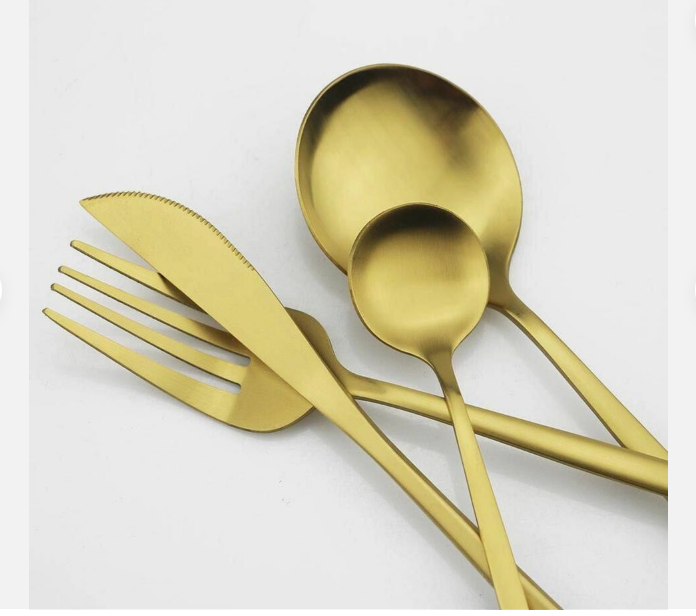 Goldenes Besteckset aus Edelstahl, bestehend aus Messer, Gabel, Löffel, auf weißem Hintergrund.