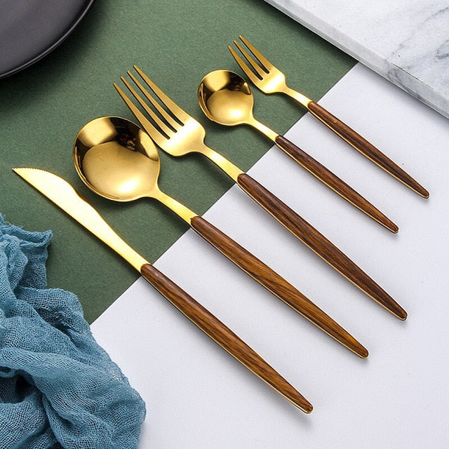 Goldenes Besteckset mit Holzgriffen auf grünem Hintergrund, modernes Design, 5-teilig.