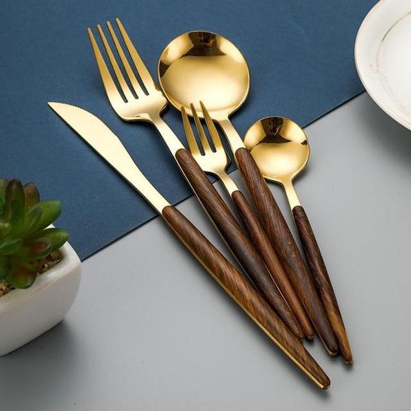 Goldenes Besteckset mit Holzgriffen, bestehend aus Messer, Gabel, Löffel auf blauem Hintergrund.