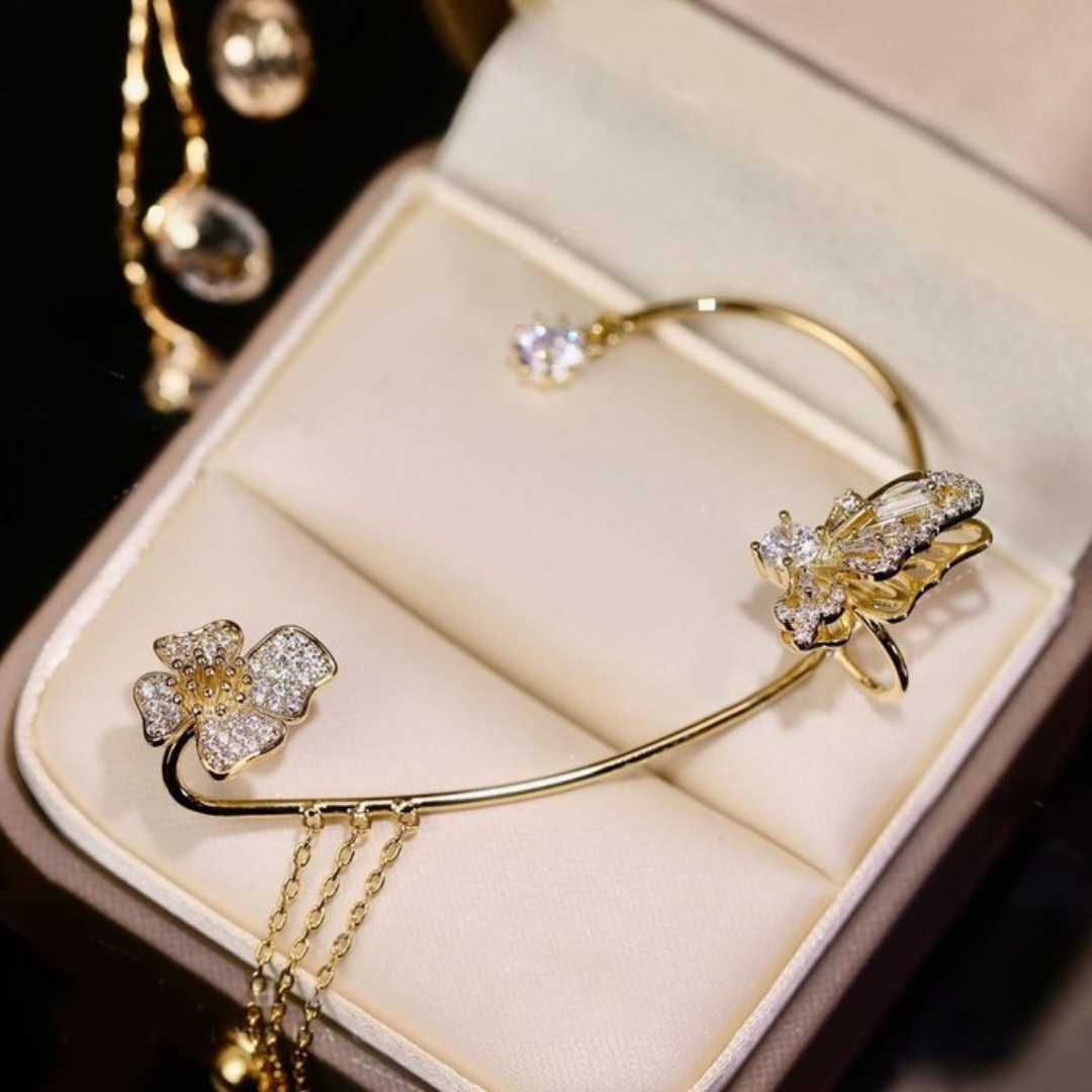 Goldenes Armband mit Blumen- und Schmetterlingsdesign, verziert mit Kristallen, in Schmuckschatulle.