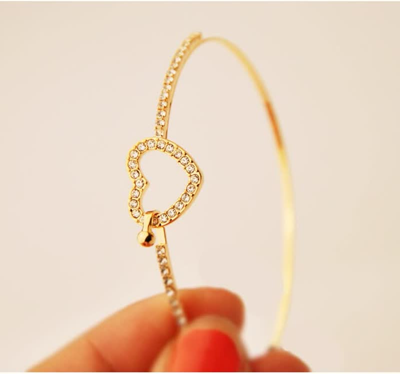 Goldenes Armband mit Herzanhänger, verziert mit Kristallen, eleganter Schmuck für Damen.
