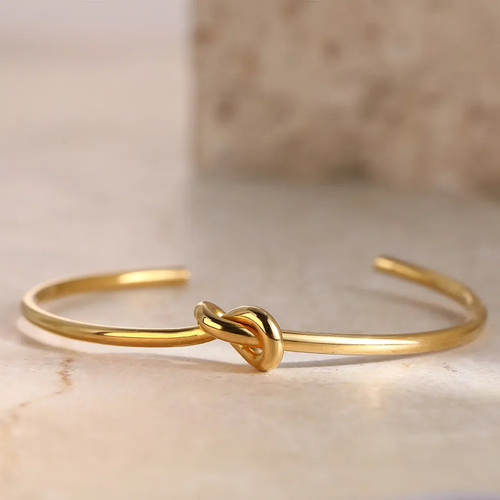 Goldenes Armreif mit Knoten-Design, minimalistischer Schmuck, elegantes Accessoire für Damen.