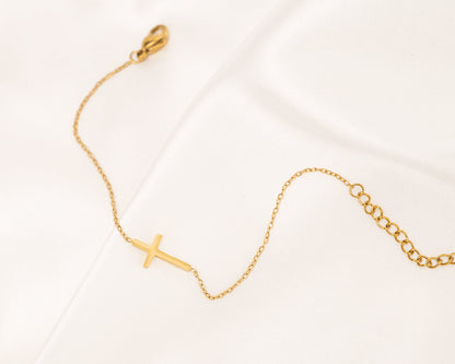 Goldenes Kreuzarmband auf Satin, filigran, Damen-Schmuck, modisch, elegant, Geschenkidee.