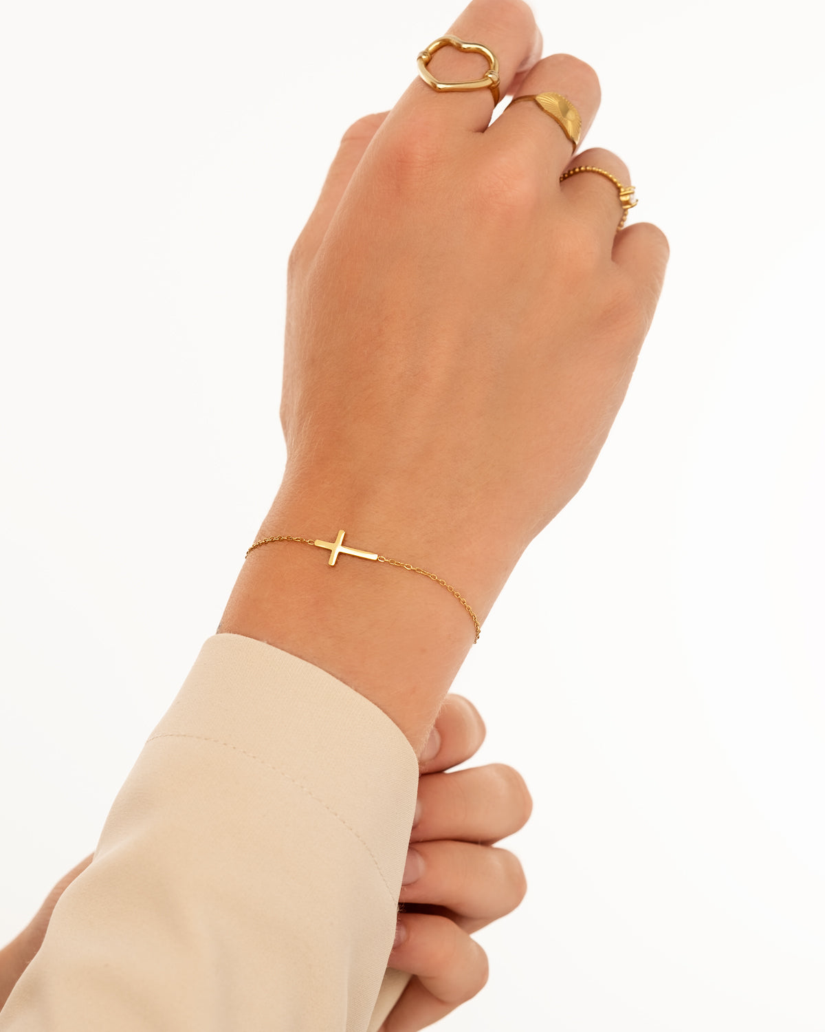 Goldenes Kreuzarmband an Hand, elegantes Schmuckstück, Damenmode, minimalistisch, Geschenkidee.