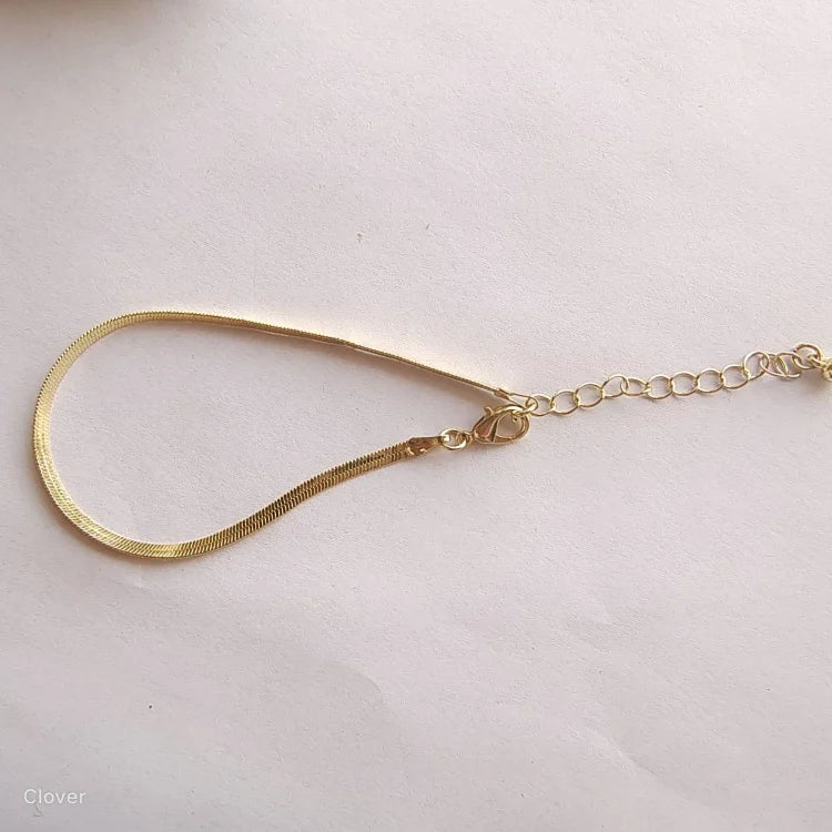 Goldenes Schlangenarmband mit verstellbarem Verschluss auf weißem Hintergrund, eleganter Schmuck.