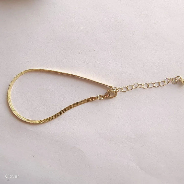 Goldenes Schlangenarmband mit verstellbarem Verschluss auf weißem Hintergrund, eleganter Schmuck.