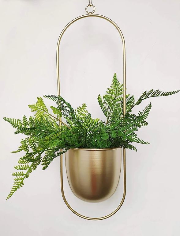 Goldener ovaler Wandpflanztopf mit grünen Farnen, hängend, modernes Dekor.