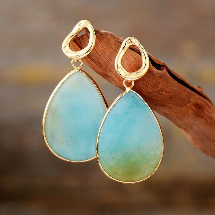 Goldene Ohrringe mit blauen Tropfenanhängern, eleganter Schmuck für Damen.