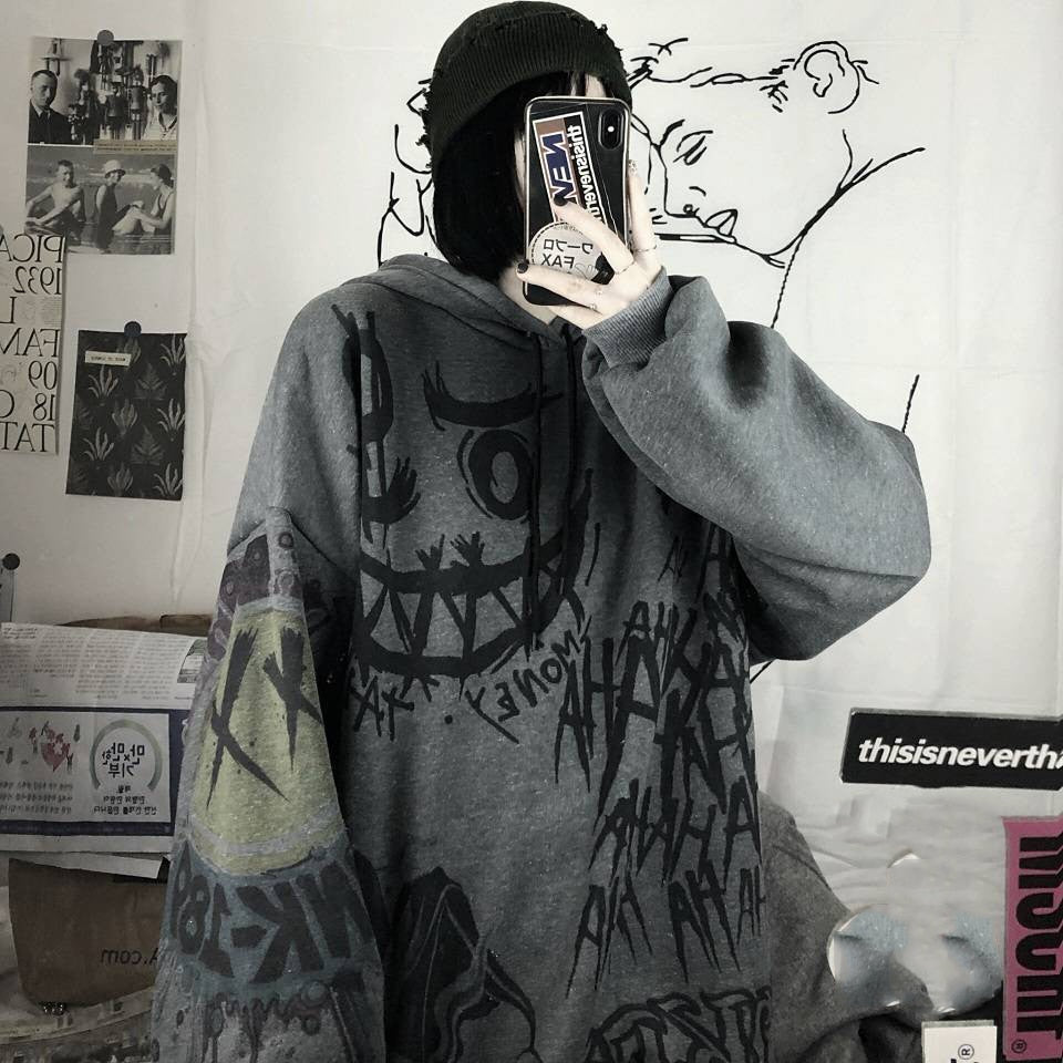 Person in grauem, grafisch bedrucktem Hoodie, Selfie, urbaner Stil, Streetwear, Mütze.