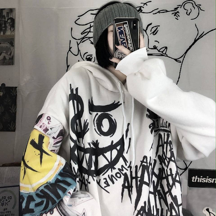 Person in weißem Graffiti-Hoodie mit Smartphone, graue Mütze, urbaner Streetwear-Stil.