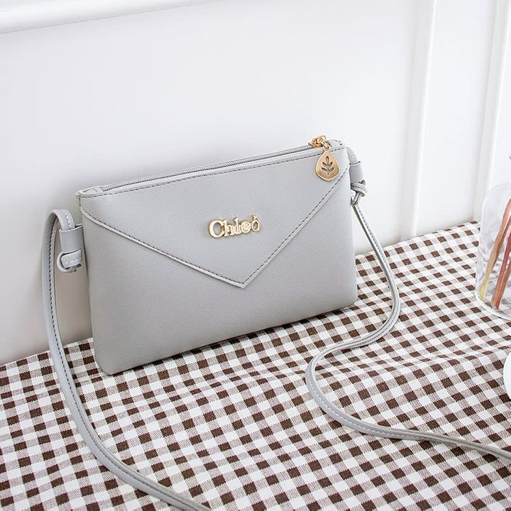 Graue Damenhandtasche aus Leder mit Schulterriemen, elegantes Design, goldene Details.