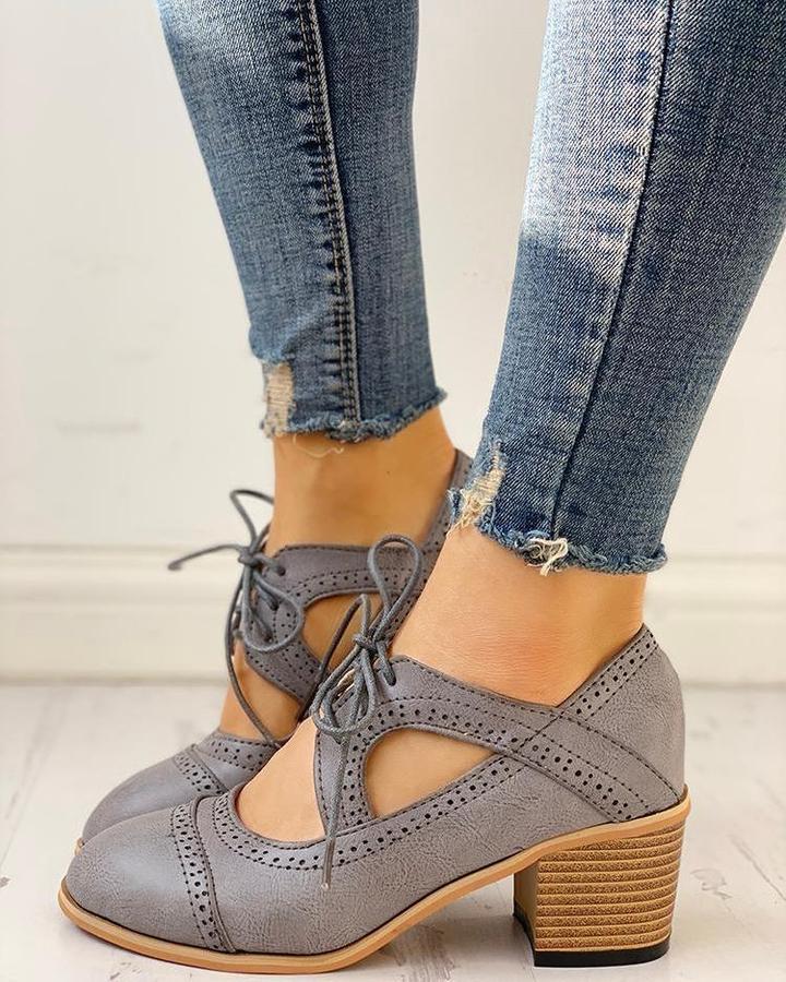 Graue Damen-Oxford-Schuhe aus Leder mit Blockabsatz, kombiniert mit zerrissenen Jeans.