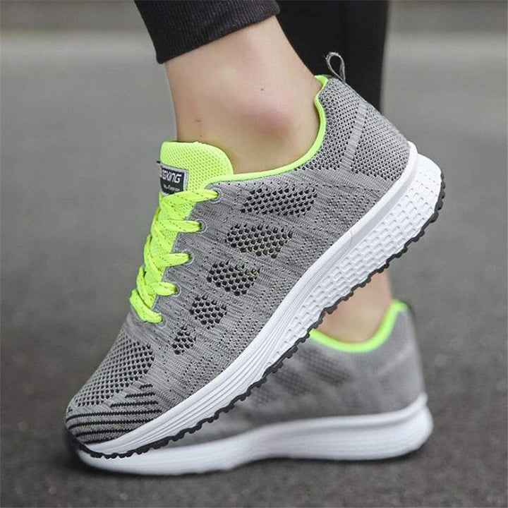 Graue Damen-Laufschuhe mit neongelben Akzenten, atmungsaktives Mesh, rutschfeste Sohle.