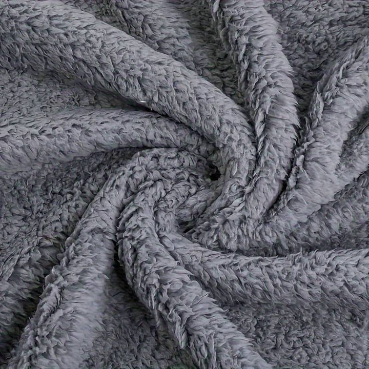 Grauer Plüschstoff, weiche Textur, ideal für Decken und Kissen, gemütlich und warm.