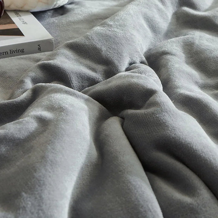 Graue, weiche Fleecedecke auf Bett, gemütlich, modern, Wohnaccessoire, Schlafzimmerdekor.