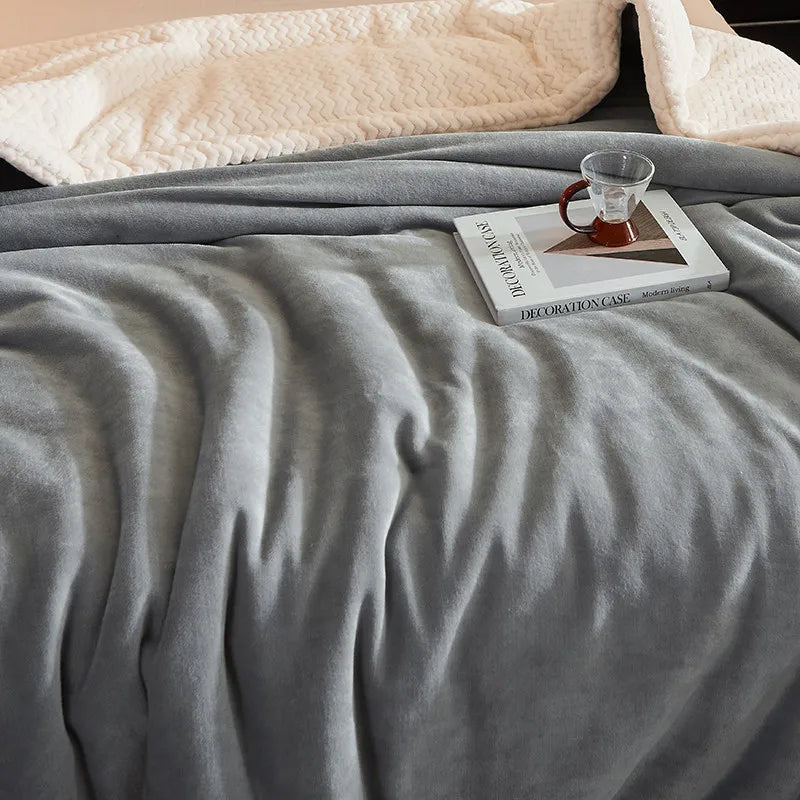 Graue Fleece-Decke auf Bett mit Buch und Teetasse, gemütliche Schlafzimmerdekoration.
