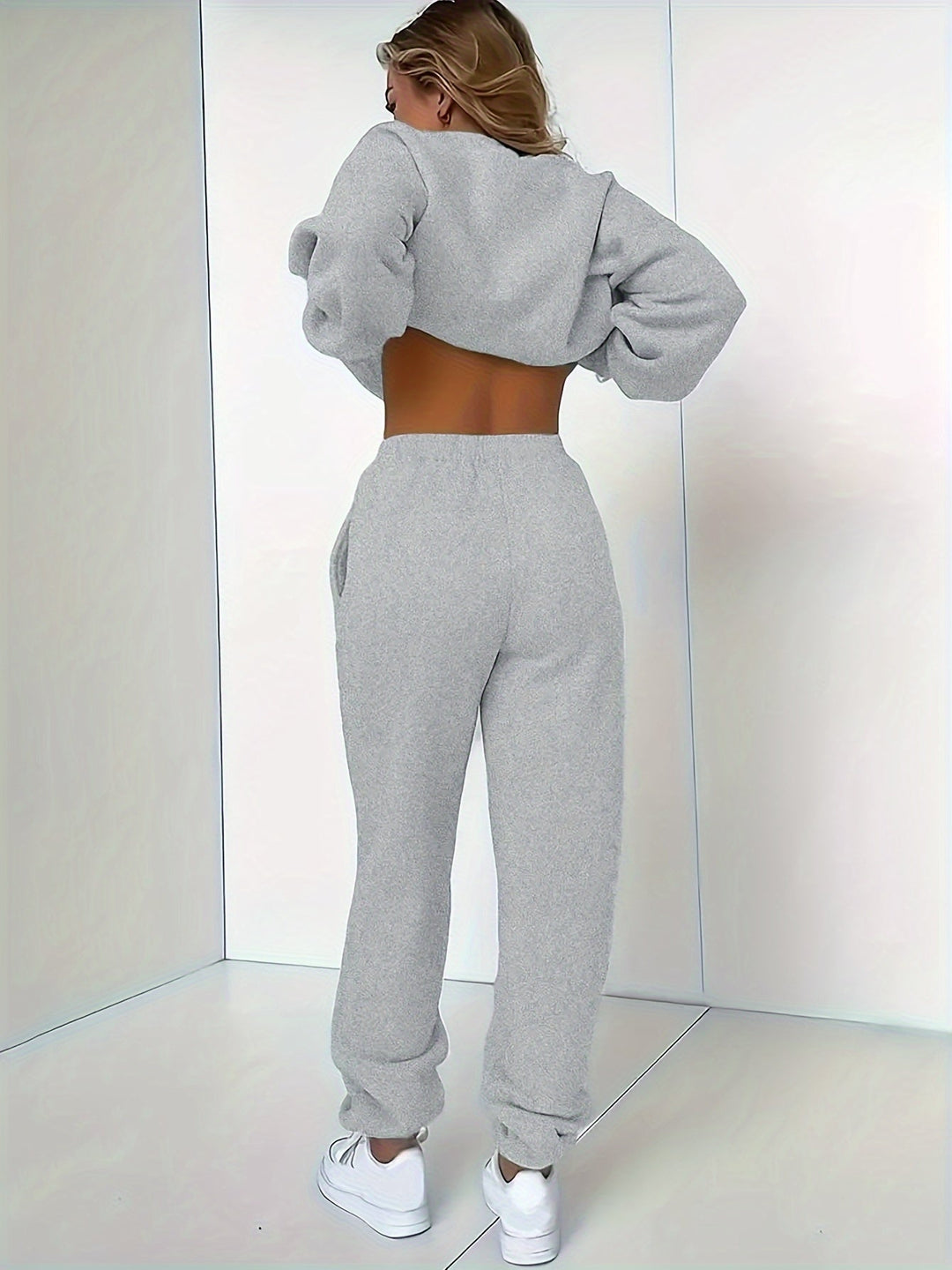 Frau in grauem Jogginganzug, Rückenansicht, Sportbekleidung, gemütlich, modisch, Indoor.