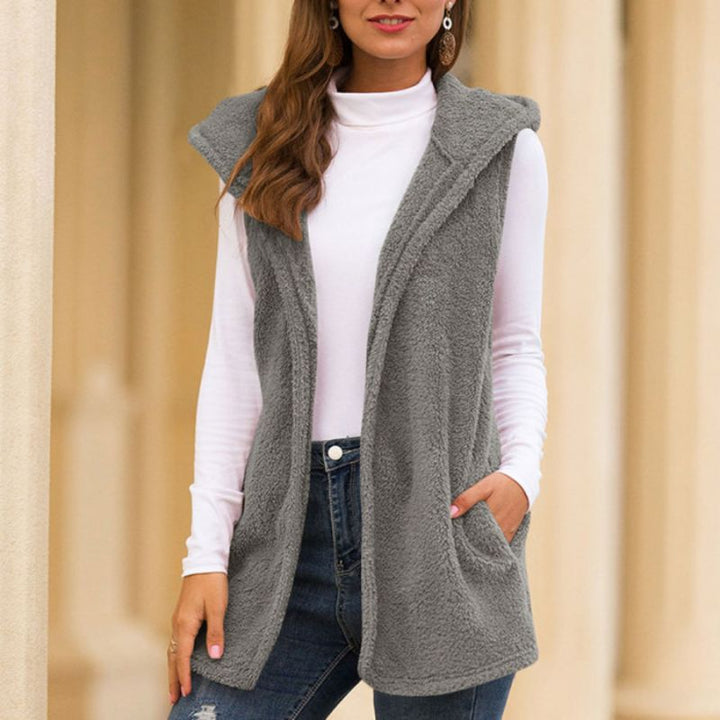 Frau trägt graue Fleeceweste mit Kapuze, weiße Rollkragenbluse, blaue Jeans, Herbstmode.