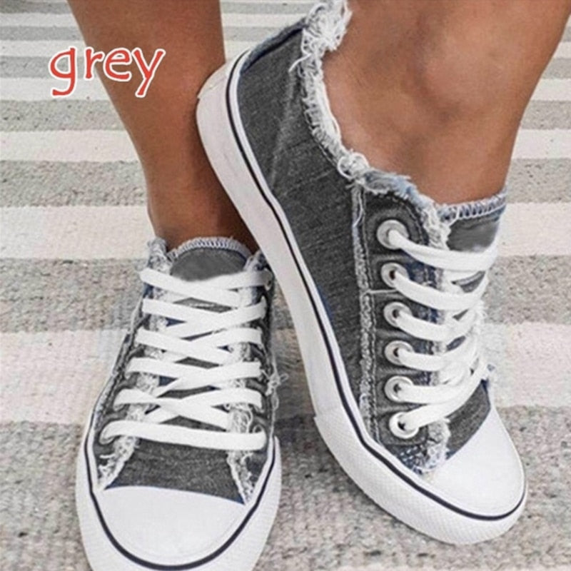Graue Damen-Sneaker aus Denim mit weißen Schnürsenkeln und Fransen, lässiger Stil.
