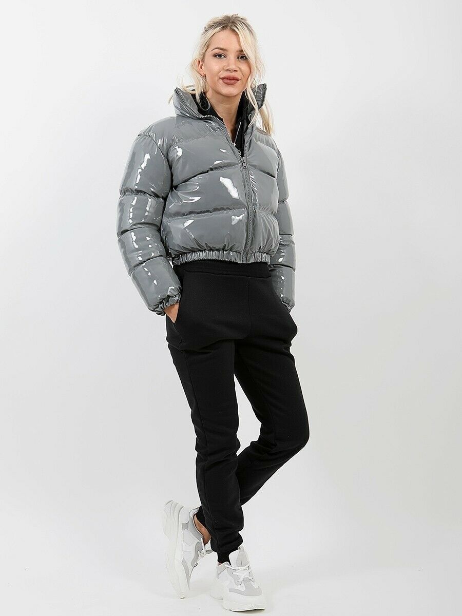Frau in grauer, glänzender Daunenjacke und schwarzer Jogginghose, modisch, Winterkleidung.