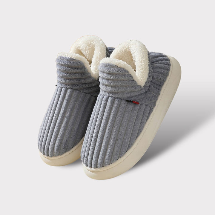 Graue Hausschuhe aus Fleece mit weißem Innenfutter, rutschfeste Sohle, gemütlich und warm.