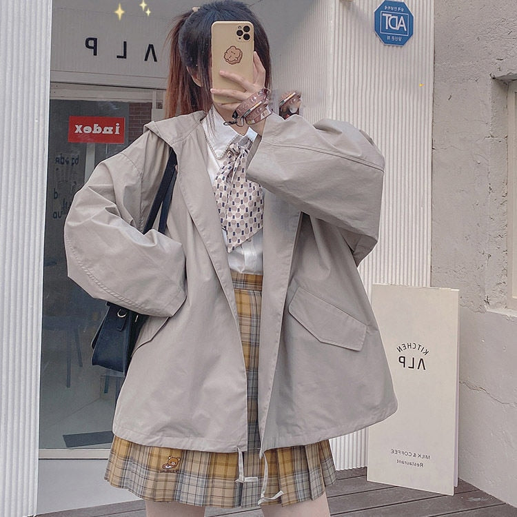 Frau in beiger Oversize-Jacke, kariertem Rock, weißer Bluse, Selfie, modisch, urban.