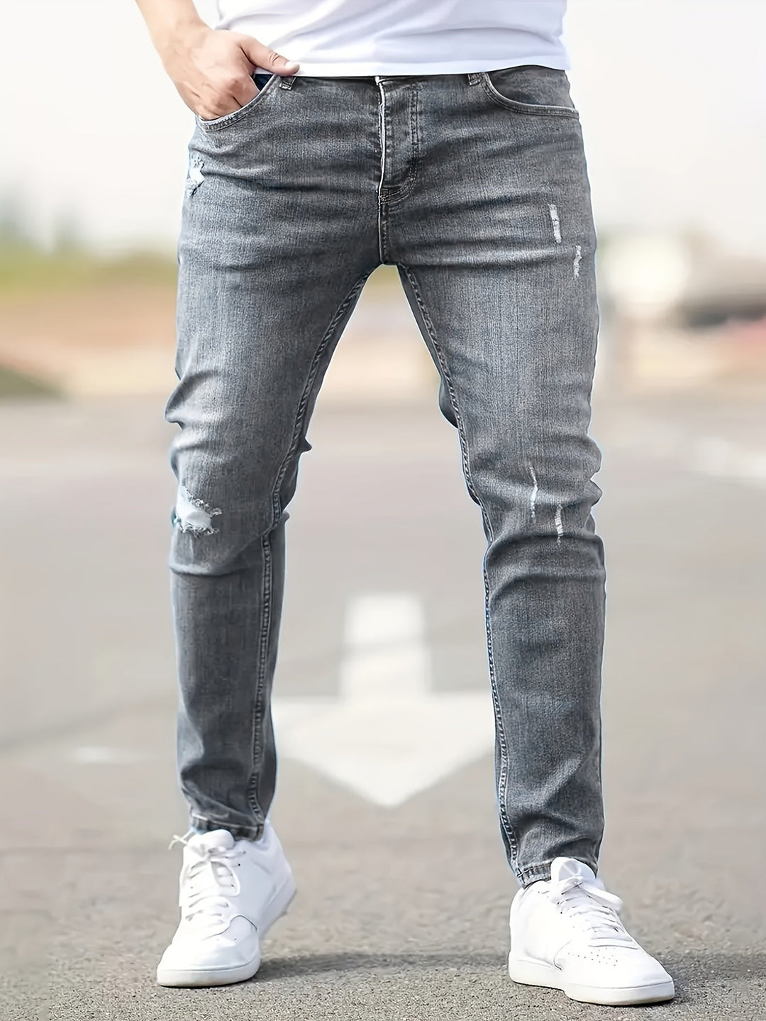 Graue Jeans für Herren, Slim Fit, mit leichten Rissen, lässiger Stil, Straßenhintergrund.