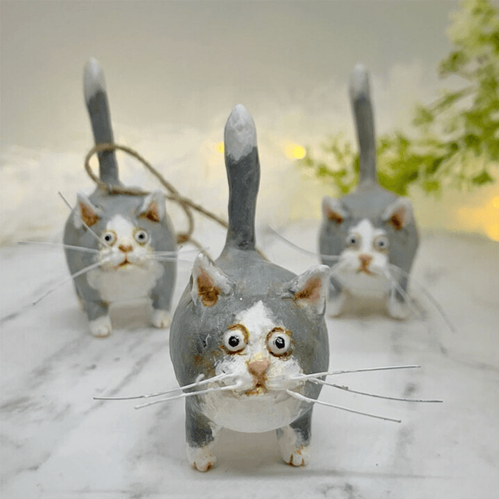 Drei graue Katzenfiguren aus Keramik mit weißen Details auf Marmortisch, handgefertigt.