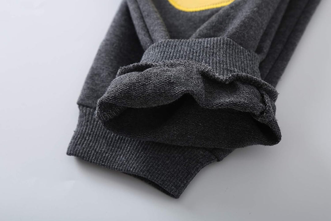Dunkelgrauer Baumwollpullover mit gelbem Aufdruck, gerippte Bündchen, weiches Material.