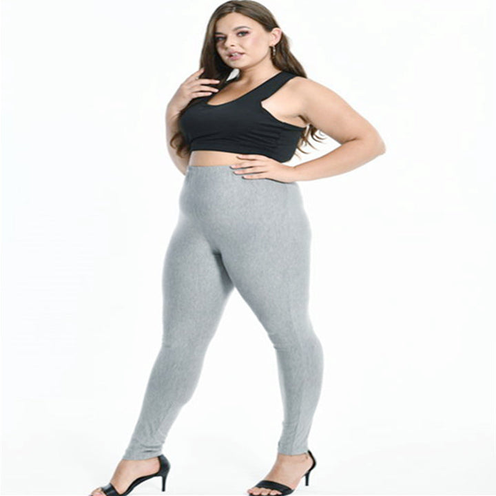 Frau in grauer Leggings und schwarzem Top, Plus-Size-Mode, elegante High Heels.