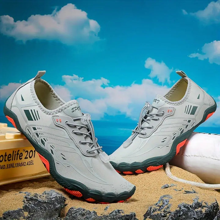 Graue Outdoor-Sportschuhe, rutschfest, atmungsaktiv, für Herren, auf Sand vor blauem Himmel.